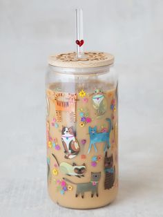 a glass jar filled with lots of different animals on it's sides and a straw sticking out of the top