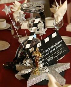 a red table topped with white plates and silver cups filled with wine glasses covered in film claps