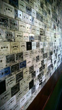 a wall covered with old cassette tapes and tape recorders in a music store or recording studio