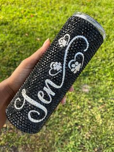 someone is holding up a black and white glitter tumbler with the word paws on it