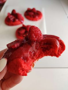 a person holding up a piece of food with raspberries on it