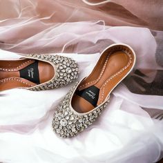 a pair of women's shoes on top of a white cloth covered bed sheet