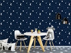 two white chairs sitting at a table in front of a wall with stars and moon decals on it