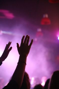 people raising their hands in the air at a concert