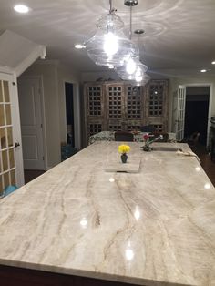 a kitchen island with marble counter tops and lights