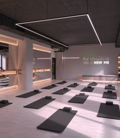 an empty gym with rows of yoga mats on the floor in front of windows and lights above them