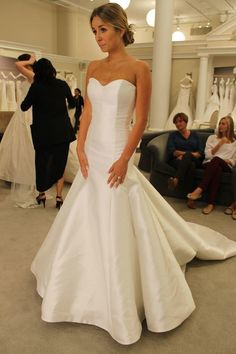 a woman standing in front of a dress on display