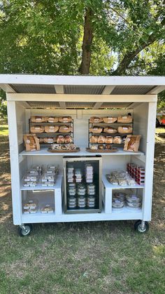 an outdoor food cart with lots of food on it's sides and shelves in the back