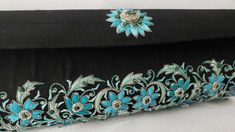 "The perfect wedding purse! A sophisticated and feminine black silk clutch bag, expertly hand embroidered by zardozi artisans. A profusion of petit blue silk flowers are inlaid with emerald gemstones. Each delicate petal and leaf is meticulously outlined with a glittery silver metallic thread, to give a sparkly, opulent 3D effect. Crowned by a beautifully embroidered blue medallion with an emerald cabochon. The word Zardozi means \"gold thread\". It is an elaborate and intricate embroidery art f Elegant Black Hand Embellished Clutch, Elegant Black Hand-embellished Clutch, Evening Clutch With Resham Embroidery Rectangular, Evening Clutch With Resham Embroidery, Traditional Embroidered Evening Bag For Formal Occasions, Traditional Embroidered Evening Bag For Formal Events, Formal Rectangular Bag With Resham Embroidery, Traditional Embroidered Formal Evening Bag, Formal Clutch With Zari Work