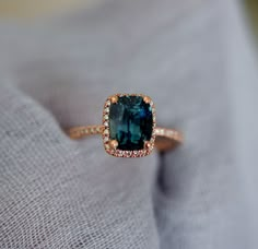 a ring with a blue stone surrounded by white and brown diamonds on a gray cloth