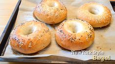 four bagels sitting on top of a pan covered in sesame seeds