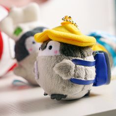 two small stuffed penguins wearing hats on top of each other's heads, sitting on a table