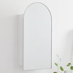 a white bathroom sink sitting under a mirror next to a vase with flowers on it