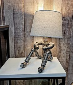 a lamp sitting on top of a white table next to a wooden paneled wall