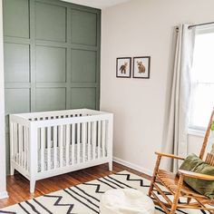 a baby's room with a white crib, rocking chair and green paneled walls