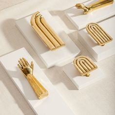 four pieces of art that are sitting on white and gold plates with forks, knives and spoons in them