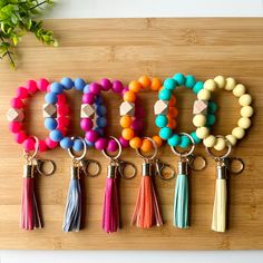 six different colored beads and tassels on a wooden board