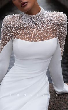 a woman in a white dress with pearls on her shoulders