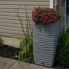 a tall planter with flowers in it next to a house