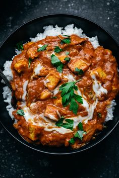 a black bowl filled with rice and chicken curry