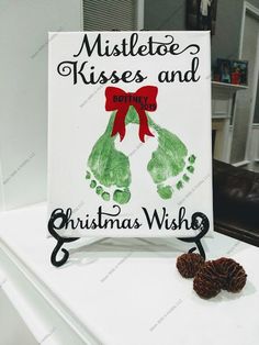 a handprinted christmas sign on top of a white table with two pine cones