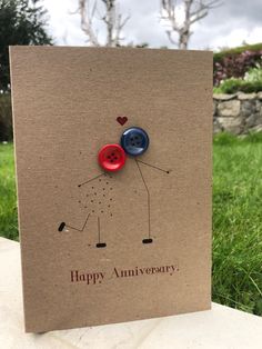 a brown card with two buttons on it and the words happy anniversary written in red