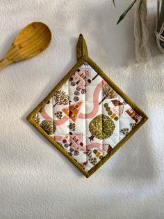 a wooden spoon sitting on top of a table next to a piece of cloth with trees