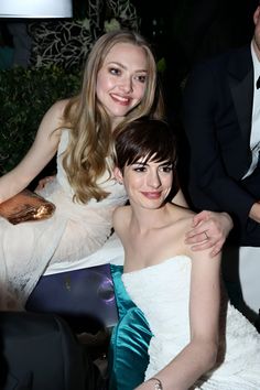 two women sitting next to each other at a formal event