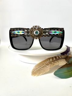 🖤Third eye funky embellished sunglasses by Alexis Exclusive - one of a kind design ✨💫 🖤The frames are black plastic and they have tinted dark lenses. Along the top they have been designed in silver diamanté trim, added jewels plus a third eye jewel in the centre.  🖤Great for festivals, carnivals, holidays etc. They'll give your outfit a real 'wow' factor, prepare to get lots of attention in these funky shades!  🖤UV protection 🖤 A unisex design  🖤Exclusive design made by myself that you won't see anywhere else. 🖤All glasses come in a black to keep them safe for delivery but please also handle with care as they are handmade. Just think of them as wearing tiny bits of wearable art.  🖤Checkout the full collection of Sunnies here :  https://www.etsy.com/uk/shop/AlexisExclusive?ref=s2-h Third Eye Sunglasses, Embellished Sunglasses, Beauty Room Decor, Small Faces, Sugar Skulls, Black Plastic, Black And Silver, Third Eye, Unisex Design