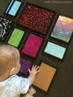 a baby playing with different colored pictures on the floor