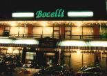 the front of a hotel at night with cars parked in front and lights lit up