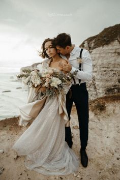 a bride and groom walking on the beach with an ocean in the background at their wedding