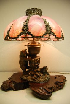 a lamp that is sitting on top of a piece of driftwood next to a wall