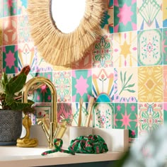 a bathroom sink with a mirror above it and colorful tiles on the wall behind it