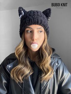 a woman wearing a black hat with cat ears on it's head and tongue sticking out