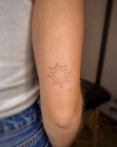 a woman's arm with a small sun tattoo on the back of her arm