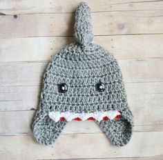 a crocheted hat with a shark's mouth on it sitting on top of a wooden floor