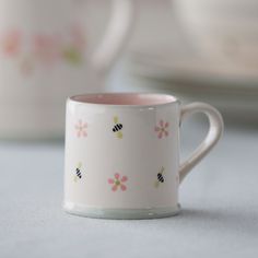 a white coffee cup with pink and yellow flowers on the inside is sitting on a table