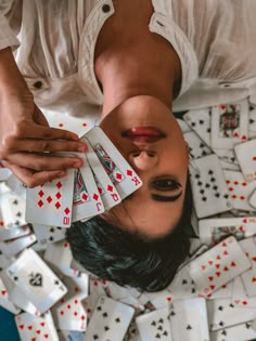 a woman is upside down with playing cards in front of her face and hands on the floor