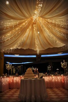 the ceiling is decorated with lights and draping for an elegant wedding reception,