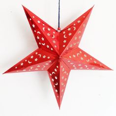 a red origami star hanging from a string with white stars on the bottom