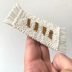 a hand holding a small white and gold beaded object