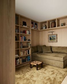 a living room with bookshelves, couch and coffee table in front of it