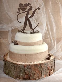 a three tiered wedding cake sitting on top of a tree stump covered in burlap