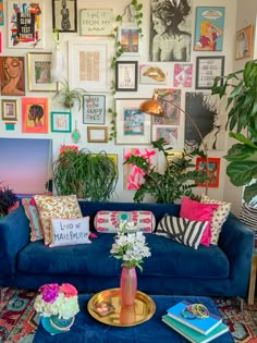 a living room filled with lots of plants and pictures on the wall next to a blue couch