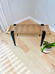 a wooden bench sitting on top of a hard wood floor next to a potted plant