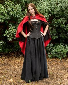 a woman in a black dress and red cape posing for the camera with her hands on her hips