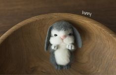 a small stuffed animal sitting on top of a wooden bowl with the word bunny written above it