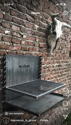 an outdoor grill is attached to the side of a brick wall with a cow skull mounted on it