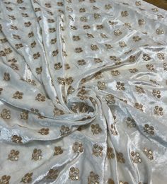 a white and gold fabric with small flowers on the bottom, along with other material